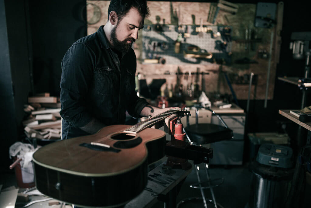 James of Well Played Gear inspecting an acoustic guitar