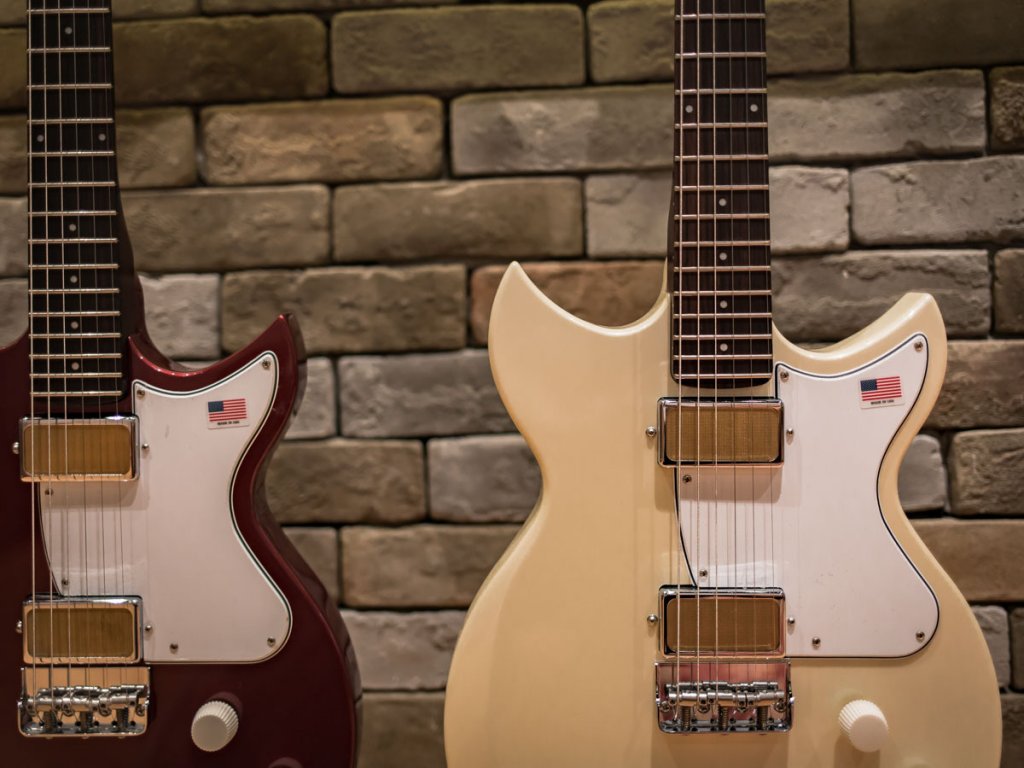 Harmony Electric Guitars hanging from a brick wall